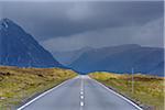 Country road with dark cloudy sky in the highlands on A82 road in Glen Coe, Scotland, United Kingdom