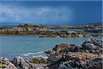 Scottish coast with rocky shoreline and storm clouds in the distance in spring at the port of Mallaig in Scotland, United Kingdom