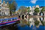 Tour boat travelling along the Herengracht Canal in Grachtengordel in the city center of Amsterdam, Holland