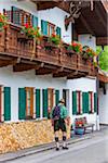 Man with backpack walking past traditional building in the town of Mittenwald in Bavaria, Germany