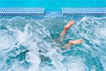 Overhead view of diving boy's feet in splashing outdoor swimming pool