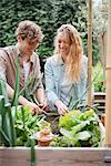 Young man and woman tending to plants in wooden troughs