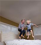 Grandson and grandmother jumping on bed