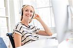 Female designer listening to headphones at creative studio  desk