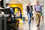 Female and male digital designers walking and talking in office