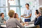 Female digital designer explaining ideas to team at conference table