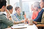 Young man showing digital design team his smartphone in office meeting