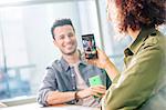 Female digital designer photographing colleague in office