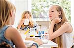Portrait of mother and daughters in kitchen having breakfast together