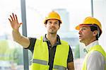 Two men wearing hi vis vest, having discussion in newly constructed office space