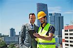 Businessman and construction worker, outdoors, looking at digital tablet