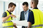 Construction workers and businessman, looking at plans