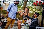 Three people at garden party, holding wine glasses, making a toast