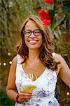 Portrait of woman at garden party, holding glass of wine, smiling