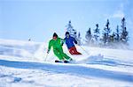 Two men skiing down snow covered ski slope, Aspen, Colorado, USA