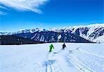 Rear view of two men skiing down snow covered ski slope, Aspen, Colorado, USA