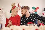 Young man and woman making faces at each other at christmas party