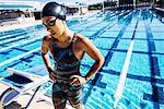 Swimmer in swimming cap and goggles catching breath by pool