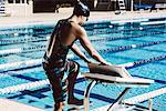 Swimmer getting onto pool diving board