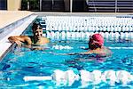 Swimmer in water at end of pool talking to friend