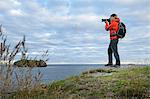 Mid adult man photographing coastline, Saint John's, NFLD, Canada