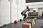 Woman jumping onto fitness box in cross training gym