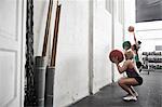 Friends throwing fitness ball against wall in cross training gym