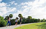 Three friends, running together outdoors, rear view, South Point Park, Miami Beach, Florida, USA