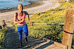 Young woman exercising, running up steps near beach, elevated view