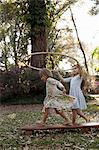 Girl holding plastic hoop above her sister's head