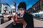 Businesswoman using mobile phone by wall on busy road, Milan, Italy