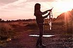 Teenage girl preparing kite on dirt track at sunset