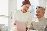 Smiling mature couple using digital tablet on sunny porch