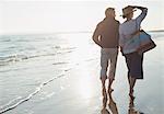 Mature couple walking on sunny ocean beach