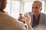Smiling senior man drinking wine, toasting wine glasses with woman at restaurant