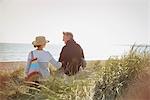 Mature couple walking arm in arm on sunny beach