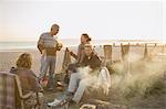 Mature couples drinking wine and barbecuing on sunset beach