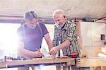 Male carpenters marking and measuring wood in workshop