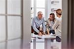 Architects reviewing, discussing blueprints in conference room meeting