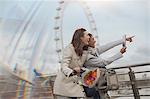 Female tourists with bicycle using digital tablet camera near Millennium Wheel, London, UK