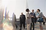 Business people talking on sunny, urban pedestrian bridge, London, UK