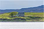 Sea bay with typical Scottish residential house in the village of Dunvegan on the Isle of Skye in Scotland, United Kingdom