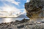 Rock face of sea cliff with honeycomb weathering and sun shining over Loch Scavaig on the Isle of Skye in Scotland, United Kingdom