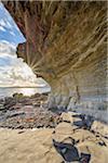 Close-up of rock face of sea cliff with honeycomb weathering and sun shining over Loch Scavaig on the Isle of Skye in Scotland, United Kingdom