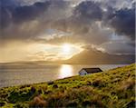 Rooftop of a house along the Scottish coast with sun shining through the dramatic clouds over Loch Scavaig on the Isle of Skye in Scotland, United Kingdom