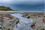 River flowing into sea bay with storm clouds over the ocean at the Isle of Skye in Scotland, United Kingdom