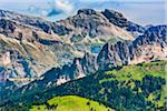 Scenic vista of the grassy mountain side and the jagged mountain tops at the Sella Pass in the Dolomites in South Tyrol, Italy