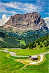 Winding road through the grassy mountain side at the Gardena Pass with the mountains of the Dolomites in the background in South Tyrol, Italy