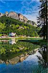 Scenic view of Hotel Lavaredo and other buildings along the shoreline and mountains reflected in Lake Misurina in the Dolomites near Cortina d'Ampezzo, Italy