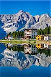 Hotel Lavaredo and other buildings reflected in Lake Misurina on a sunny day in the Dolomites in Veneto, Italy